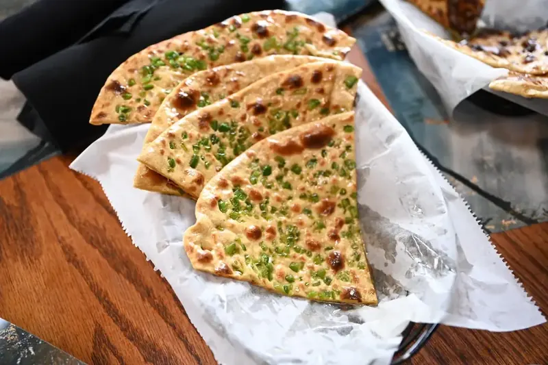 Garlic Naan – Pillowy naan bread brushed with garlic butter, baked fresh in our tandoor oven. | SPICE ROOM Denver